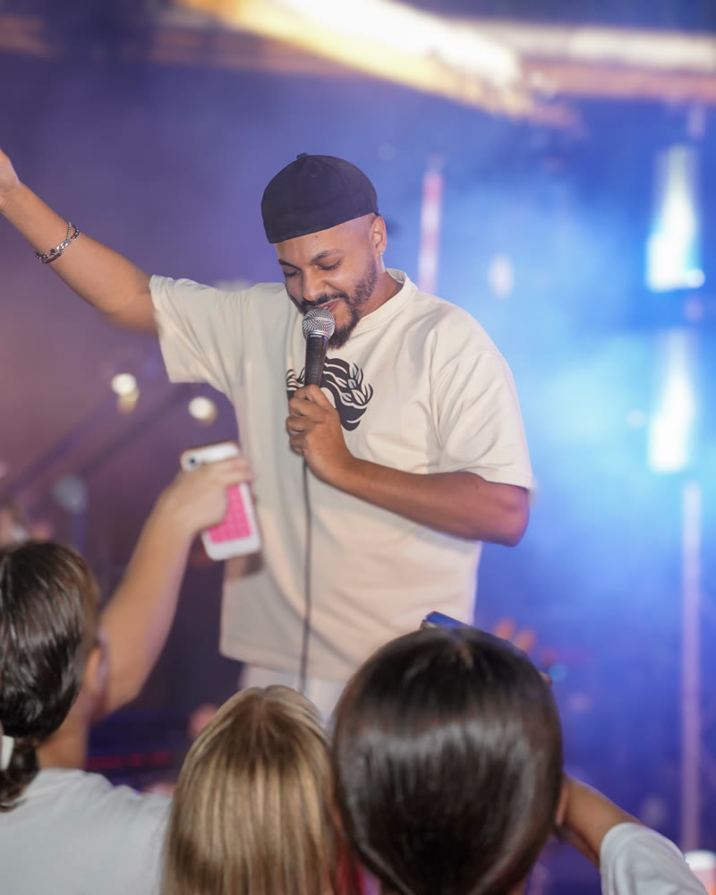 מאור גמליאל על הבמה עם מיקרופון, אורות כחולים וקהל של ילדים מולו